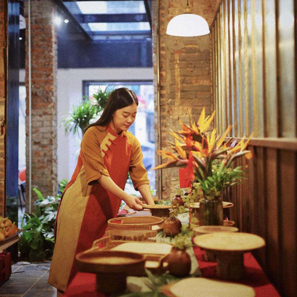 Nhân viên Mai Catering đang bố trí khay đĩa trên bàn tiệc bằng cách tạo lớp cao thấp để tăng tính thẩm mỹ và sự thuận tiện trong sắp xếp món ăn
